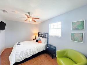 a bedroom with a bed with a ceiling fan and a green chair at Unobstructed Oceanfront SAND DOLLAR Unit 7 Beach Pad! in Surfside Beach +25 photos