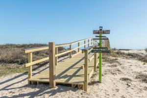 - une promenade en bois sur la plage avec un panneau de plage dans l'établissement The Blue Haven - Cute Beach Bungalow With Easy Access to Sand and Gulf Waters!, à Surfside Beach