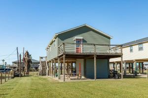 a house with a deck on the side of a yard at Casa de las Olas - Huge Fenced Yard, Massive Outdoor Shower, Great Breezes From Deck! in Surfside Beach