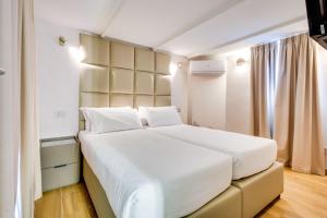 a bedroom with a large white bed and a window at Relais Badoer in Rome