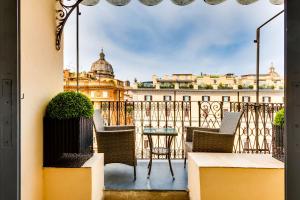 a balcony with chairs and a table and a building at Relais Badoer in Rome