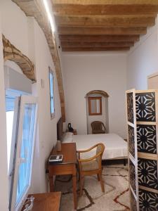 a bedroom with a bed and a desk and a table at Casa Maranaty in Vejer de la Frontera