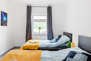 two beds in a room with a window at Stanion Luxurious 3 Bedroom Modern House Northamptonshire, Double, Twins, Single, Free Parking, Free Wi-Fi, Pets, Up to 8 Sleeps, 4 Smart TVs in Corby