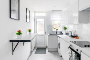 a white kitchen with white appliances and a window at Stanion Luxurious 3 Bedroom Modern House Northamptonshire, Double, Twins, Single, Free Parking, Free Wi-Fi, Pets, Up to 8 Sleeps, 4 Smart TVs in Corby
