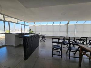 Una habitación grande con sillas, mesas y ventanas. en Apto completo super confortável e moderno próximo Metro Vila Madalena, en São Paulo