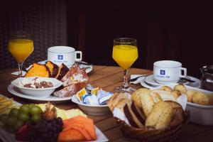 Una mesa cubierta con platos de comida y vasos de jugo de naranja. en La Dolce Vita Park Hotel, en São José dos Pinhais