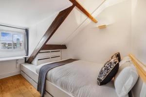 ein kleines Schlafzimmer mit einem Bett und einem Fenster in der Unterkunft Marais Rooftop Apartment in Paris