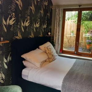 a bed with pillows on it in a room with a window at The Nook- Cotswold guest room in Mickleton
