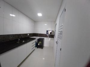 a white kitchen with a sink and a trash can at Espaço Brisa do Mar in Olinda