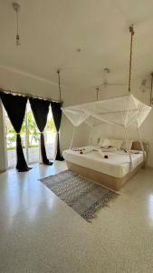 a bedroom with a white bed with a canopy at Mwezi - Maisha Resort in Watamu