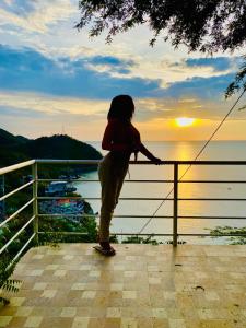 a woman standing on a railing watching the sunset at Sol y Luna apartment in Santa Marta