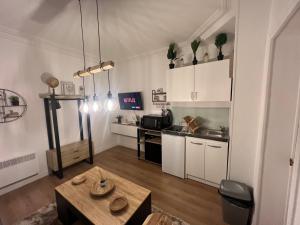 eine Küche mit weißen Schränken und einem Tisch im Zimmer in der Unterkunft Studio cosy aux portes de Paris - 2PAX in Saint-Ouen