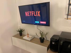 einen Fernseher an einer Wand mit einem Netflix-Schild drauf in der Unterkunft Studio cosy aux portes de Paris - 2PAX in Saint-Ouen