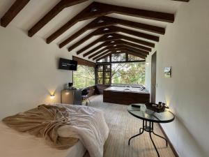 una camera da letto con un letto e un tavolo in una stanza di Cabañas Tahamí con jacuzzi cerca al Aeropuerto a Guarne