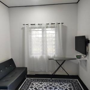a living room with a couch and a window at Nour homestay Rumah B in Kaki Bukit