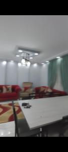 a room with a white table and chairs and a room with red chairs at شقة فندقية للايجار in Nazlat as Sammān