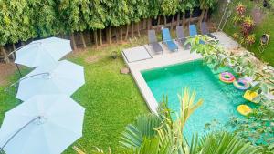 een achtertuin met een zwembad met stoelen en parasols bij Villa Le Cervin in Cocody