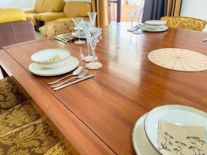 een houten tafel met borden en glazen erop bij Villa Le Cervin in Cocody