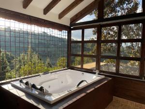 una grande vasca da bagno in una stanza con finestre di Cabañas Tahamí con jacuzzi cerca al Aeropuerto a Guarne