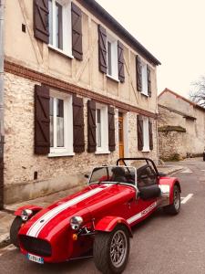 czerwony samochód zaparkowany przed budynkiem w obiekcie Maison d'hôtes L'ormerie- Au coeur de la ville médiévale w mieście Provins