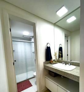 a bathroom with a sink and a shower and a mirror at Apartamento Marina Vip in Salvador