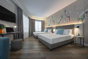 a hotel room with two beds and a tv at IH Hotels Milano Centrale in Milan +80 photos