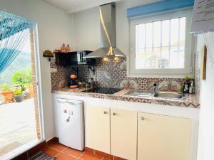 a kitchen with a sink and a refrigerator and a window at Casita Acacia in Viñuela