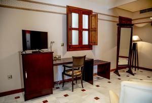 a room with a desk with a television and a chair at Hotel Don Miguel Plaza in Berja