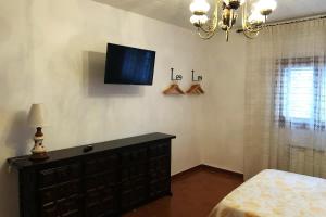 a bedroom with a dresser and a tv on the wall at Ave Fénix in Calaceite