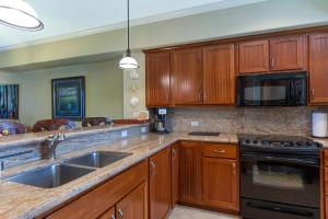 een keuken met houten kasten en een spoelbak bij G22 Waikoloa Beach Villas in Waikoloa