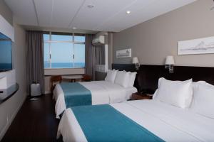 a hotel room with two beds and a flat screen tv at Sol Ipanema Hotel in Rio de Janeiro