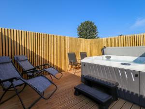 a deck with chairs and a hot tub and a fence at Beach Haven in Anderby
