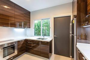 eine Küche mit Holzschränken und Spüle und einem Fenster in der Unterkunft Sukhumvit 16 Townhouses, InHome Luxury Residences in Bangkok