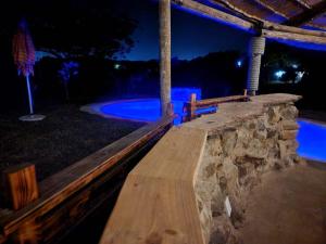 a wooden bench in front of a stone wall at night at La Hacienda in uMhlali
