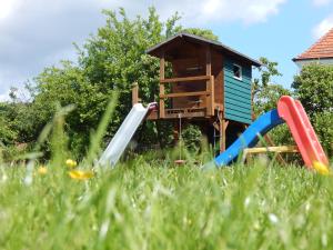 a playground with a house and slides in the grass at Reiter- und Ferienhof Redder in Bad Driburg
