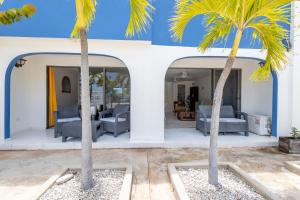 two palm trees in front of a house at Lighthouse Beach Resort with Ocean View in Kralendijk