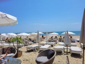 ein Strand mit Stühlen und Sonnenschirmen und Menschen im Sand in der Unterkunft Studio - La Grande Motte in La Grande-Motte