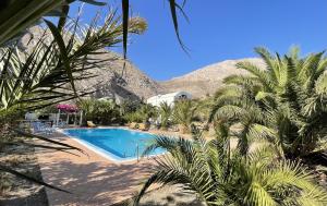 a swimming pool with palm trees and a mountain at HONES - RELAX HOUSE in Perissa