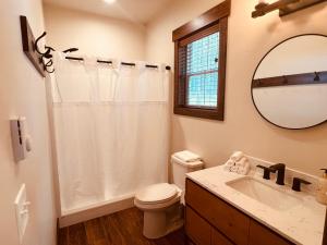 Un baño con inodoro, lavabo y espejo. en Elk Ridge Village 201A Cozy Cabin with views of Flathead Lake and the mountains, en Lakeside