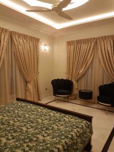 a bedroom with two chairs and a bed and curtains at Royal Palace Hotel in Islamabad +14 photos