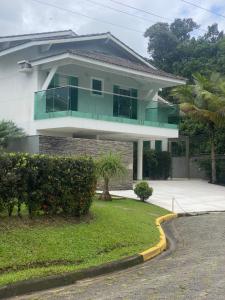 a house with a green balcony on top of it at Casa de Praia em Condomínio Hanga Roa Bertioga in Riviera de São Lourenço