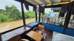 a room with a table and chairs and a view of a river at Baan mae khian homestay in Phra Nakhon Si Ayutthaya