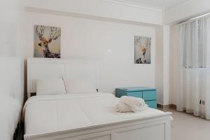 a white bedroom with a bed and two pictures on the wall at Oceanfront 3 Bedroom With Jacuzzi and Pool in Santo Domingo +35 photos