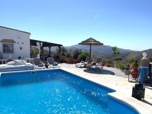 ein Pool mit Stühlen und einem Sonnenschirm und ein Haus in der Unterkunft Casita Risa in Viñuela