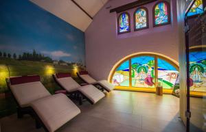 a room with white chairs and stained glass windows at H&ocirc;tel Le Cep in Beaune