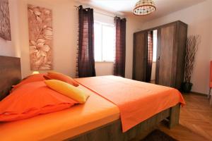 a bedroom with a bed with an orange comforter at Apartment Garden M&M in Dubrovnik