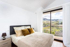 a white bedroom with a bed and a large window at Two apartments 250m from las americas Beach in Playa de las Americas