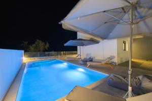 a swimming pool at night with an umbrella at Villa Vasaltis & Selestitis in Gennadi