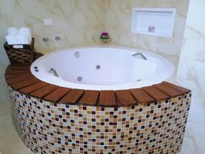a bath tub with a wooden deck around it in a bathroom at Chalé Recanto in Visconde De Maua