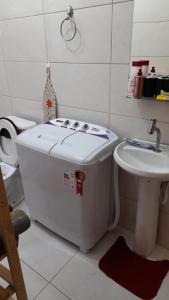 a small bathroom with a washing machine and a sink at Lindo Flat em Maresias in São Sebastião